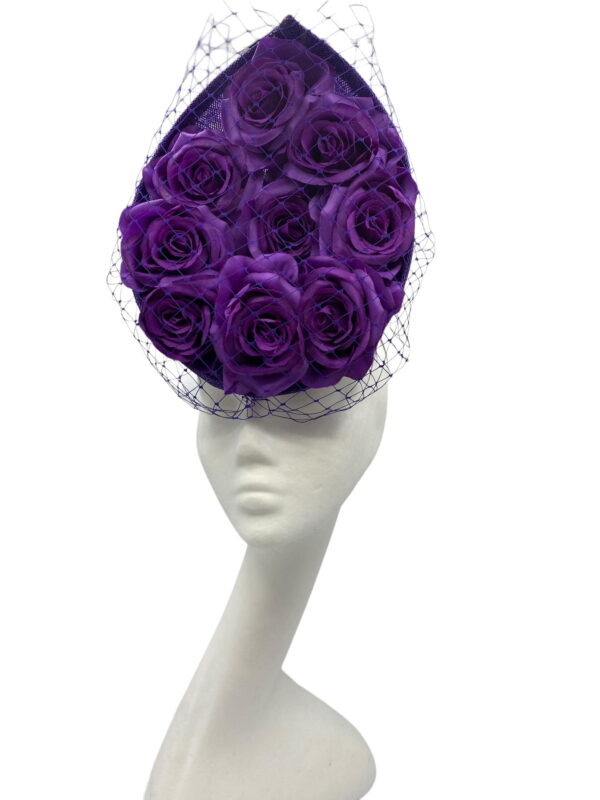 Cadbury purple coloured percher hat with purple roses in the centre and finished with a purple netting over the headpiece.